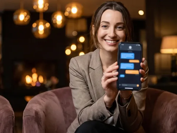 Гост в лоби на хотел държи телефон с разговор с ISKA Assistant.
